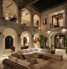 a living room filled with white furniture and lots of windows on the side of it