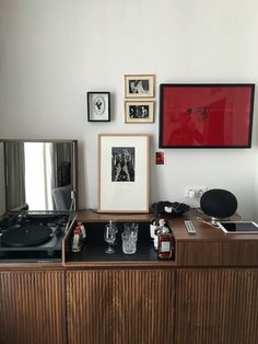 an old record player sits on top of a wooden cabinet in front of a mirror