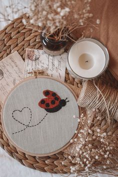 a ladybug embroidered on a piece of fabric next to a candle