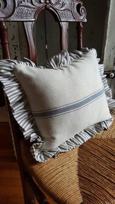 a chair with a pillow on top of it next to a wooden chair and wall