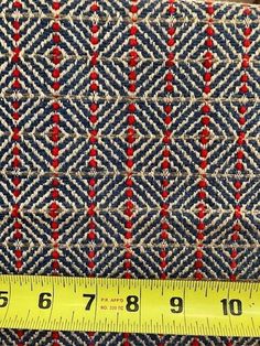 a measuring tape is next to a blue and red patterned fabric with small squares on it