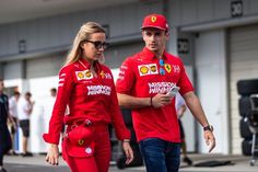 a man and woman dressed in red are walking down the street with other people behind them