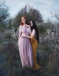 two women in long dresses standing next to each other