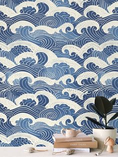 a blue and white wave wallpaper with books on the table in front of it