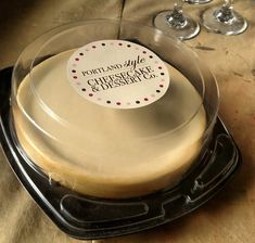 there is a cake in the pan on the table with wine glasses behind it and a sticker that says portas cafe cheesecake cheese