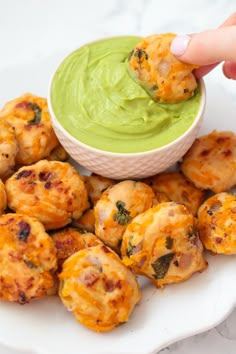 a person dipping some kind of food into a small white bowl with guacamole in it