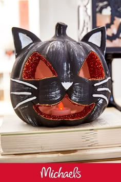 a black cat pumpkin sitting on top of a stack of books