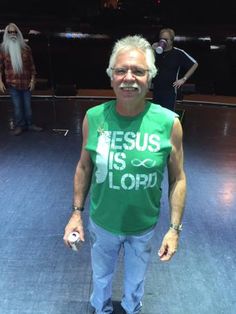 a man in a green shirt is standing on a stage with other people behind him