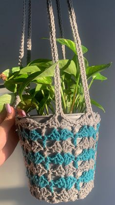 a crocheted planter hanging from a chain with a potted plant in it