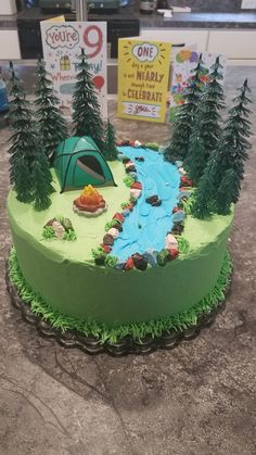 a green cake with trees and a tent on it