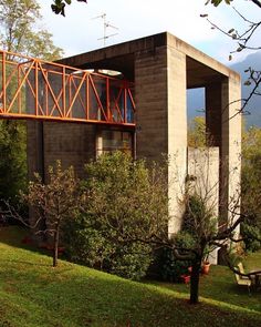 a small house with an orange railing on the roof and balcony above it is surrounded by trees