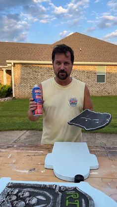 a man holding up a can of beer next to a cake