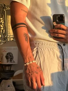 a man with tattoos on his arm is holding a cell phone and wearing white shorts