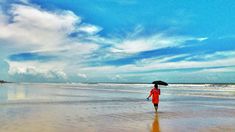 a person walking on the beach with an umbrella