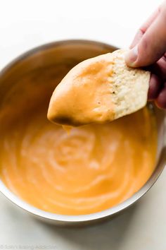 a person dipping some food into a bowl