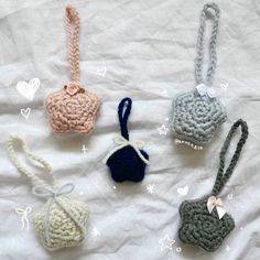 four crocheted purses sitting on top of a white sheet with hearts around them