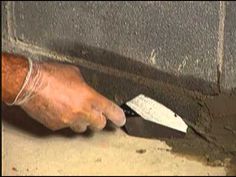 a man is holding a knife in front of a brick wall with cement on it