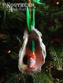 an ornament hanging from a christmas tree decorated with hot sauce and green ribbon