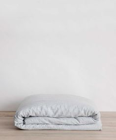 an unmade bed sitting on top of a wooden floor next to a white wall