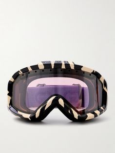 a pair of ski goggles sitting on top of a white surface with zebra print