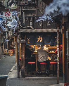 a man sitting at a table in front of a store