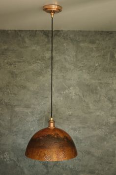 a light hanging from a ceiling in a room with concrete walls and flooring on the wall