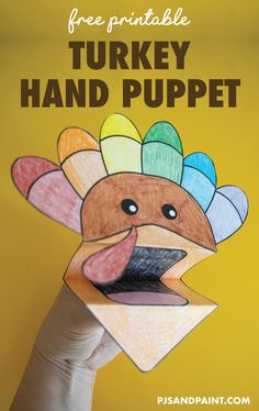 a hand holding up a paper turkey with the text free printable turkey hand puppet