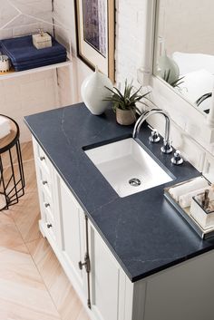 a bathroom sink sitting under a mirror next to a counter top with a potted plant on it