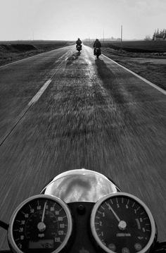 two motorcyclists are riding down the road in front of an approaching car