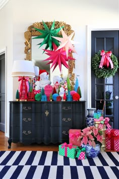 christmas presents are piled on top of an old dresser in the entryway to a home