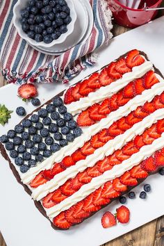 an american flag cake with strawberries and blueberries on the plate next to it