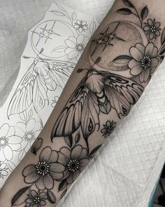 a black and white tattoo with flowers on the arm