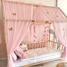 a pink canopy bed with curtains and pillows