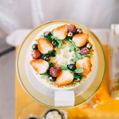 a cake with strawberries, blueberries and other toppings on a gold plate