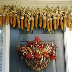 corn on the cob hanging from a door with fall foliage and pumpkins in it