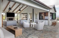 an outdoor living room with stone flooring and white furniture on top of the patio