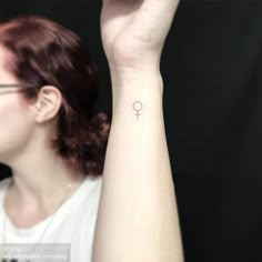 a woman with a small tattoo on her left wrist holding up the word love in front of her right arm