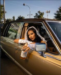 a woman in a wedding dress leaning out the window of a car holding a beer