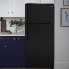 a black refrigerator freezer sitting inside of a kitchen next to white counter tops and blue cabinets