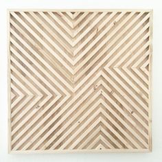 a wooden wall hanging on the side of a white wall with an abstract design made out of strips of wood