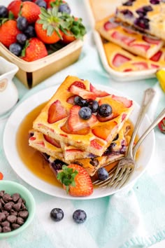 a white plate topped with waffles covered in fruit next to chocolate chips and strawberries