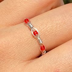 a woman's hand wearing a ring with red stones on the inside of it