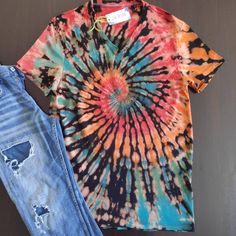 a tie - dyed shirt and ripped jeans are sitting on the floor next to each other