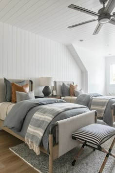 a bedroom with two beds and a ceiling fan in the corner, along with an area rug on the floor