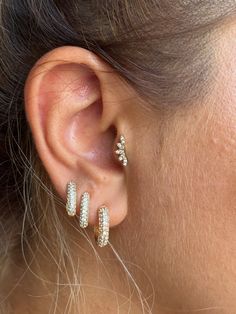 a close up of a woman's ear wearing gold and white diamond hoop earrings