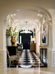 a hallway with black and white checkered flooring, large vases on the end table