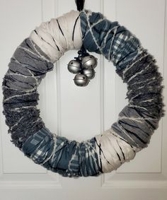 a christmas wreath with bells hanging from the front door, decorated with yarn and twine