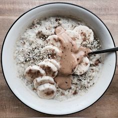 a white bowl filled with oatmeal and bananas covered in peanut butter on top of a wooden table