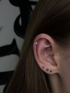 a woman's ear with three piercings on it