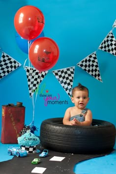 a baby sitting in a tire with some balloons